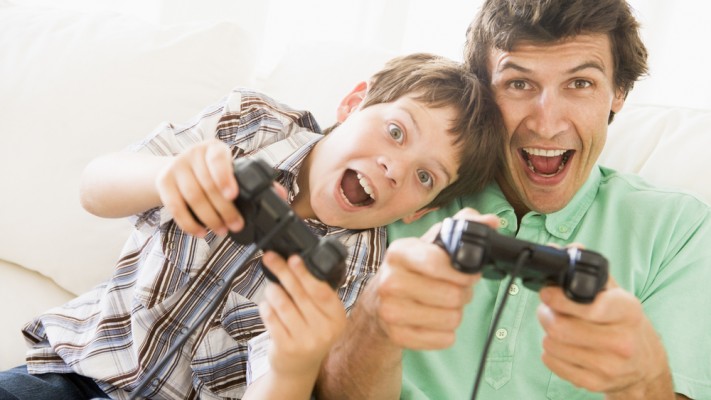 Man and young boy with video game controllers smiling